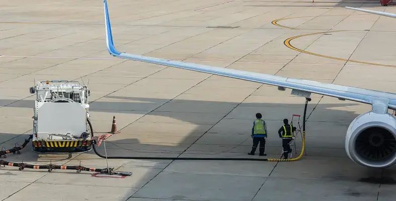 Image of two workers filling a plane with fuel